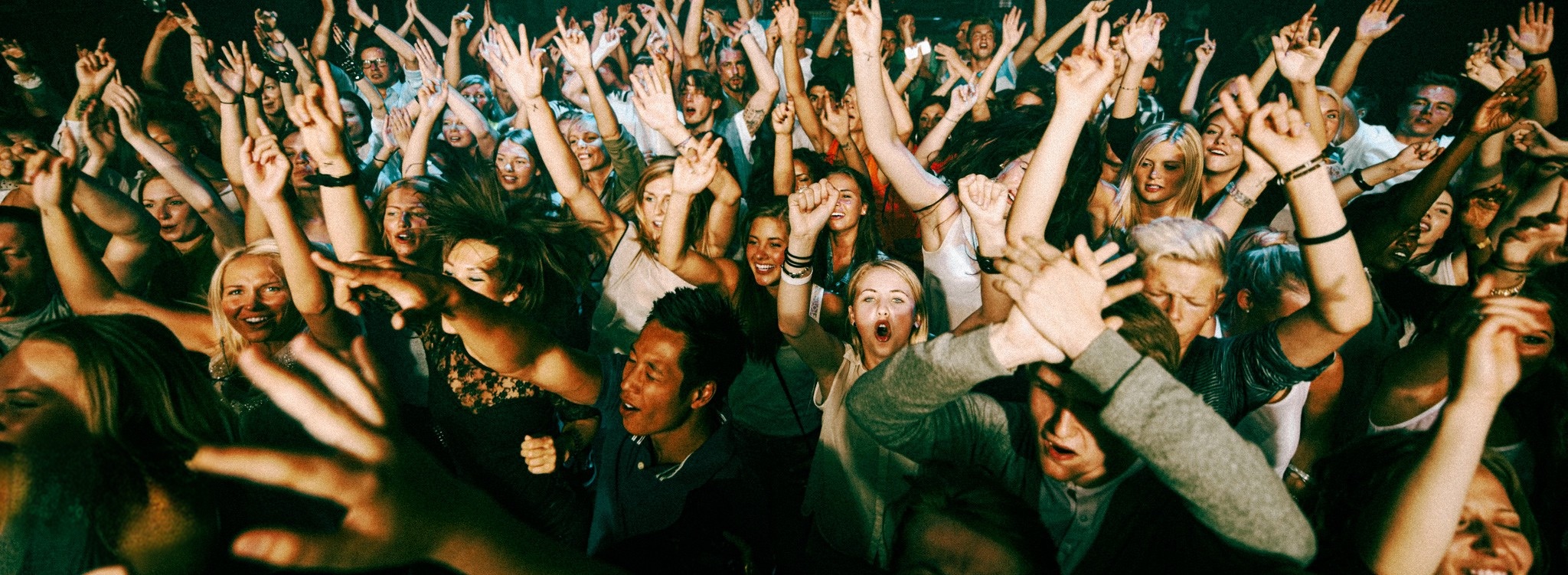 a crowd at a live show, hands raised toward the stage